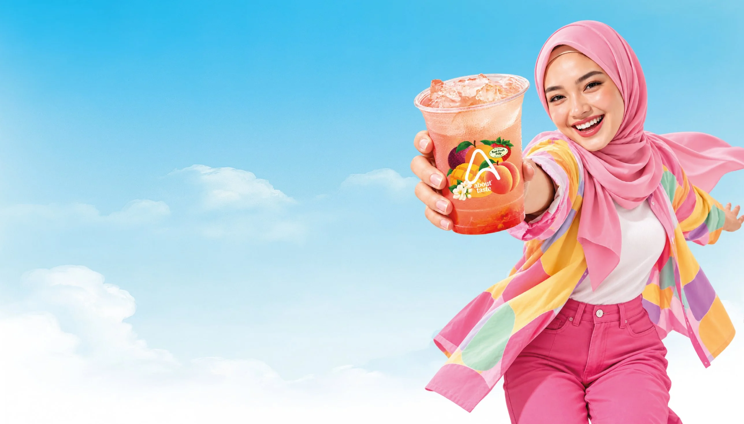 A smiling young woman in a pink hijab holding out an About Taste fruit drink against a blue sky